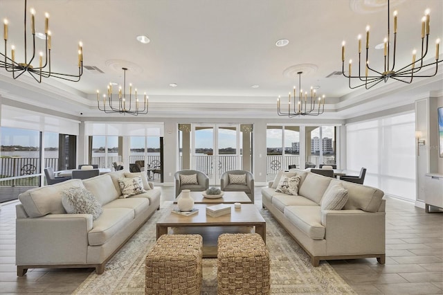 living room with crown molding, a chandelier, and a raised ceiling