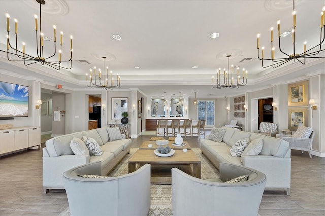 living room featuring a notable chandelier, ornamental molding, and a raised ceiling