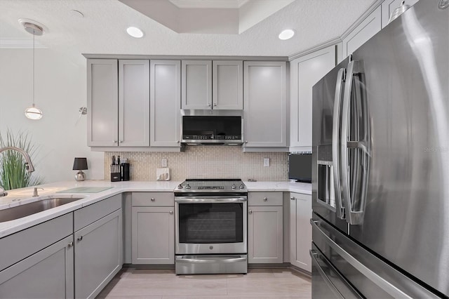 kitchen featuring appliances with stainless steel finishes, sink, gray cabinetry, and decorative light fixtures