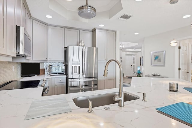 kitchen featuring sink, backsplash, stainless steel refrigerator with ice dispenser, stove, and light stone counters