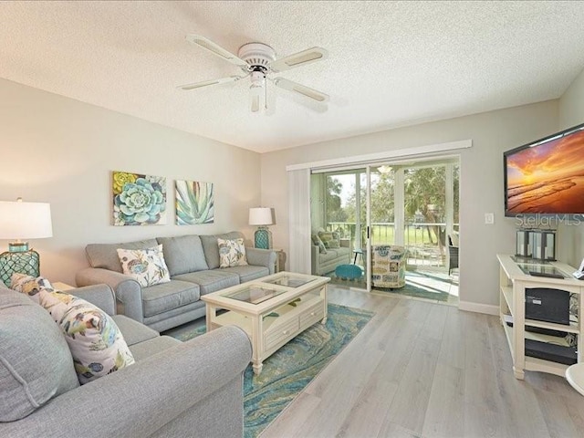 living area with a textured ceiling, baseboards, light wood-style flooring, and a ceiling fan