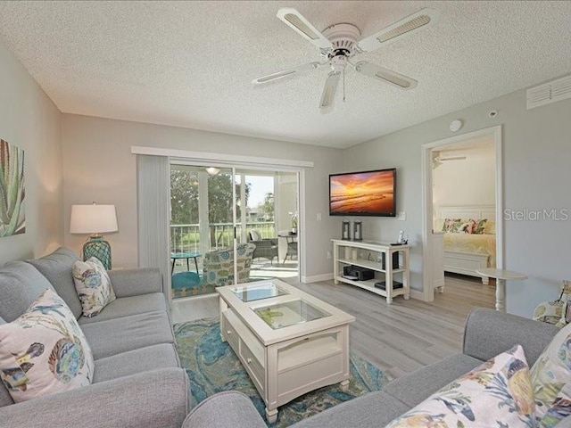 living area with visible vents, ceiling fan, a textured ceiling, light wood-type flooring, and baseboards