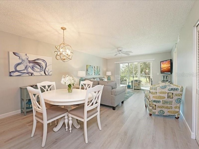 dining room featuring light wood-style flooring, baseboards, a textured ceiling, and ceiling fan with notable chandelier