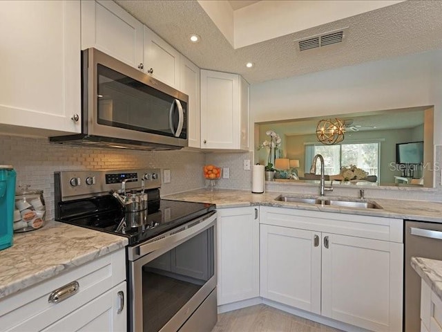 kitchen featuring visible vents, appliances with stainless steel finishes, a textured ceiling, white cabinetry, and a sink