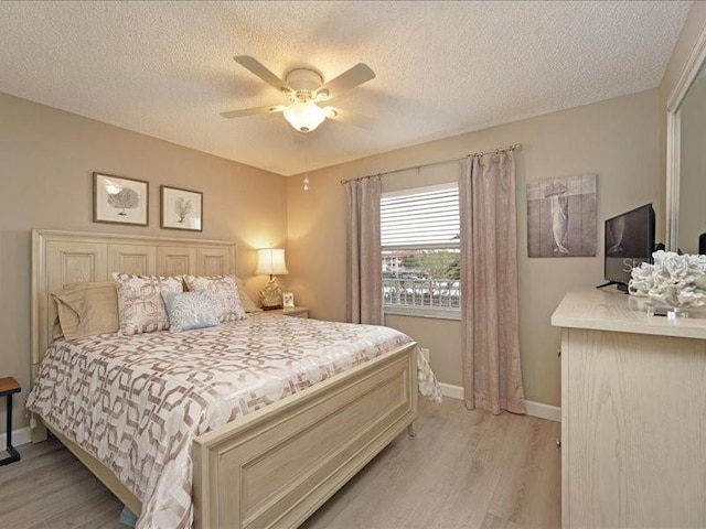 bedroom featuring baseboards, a textured ceiling, and light wood finished floors