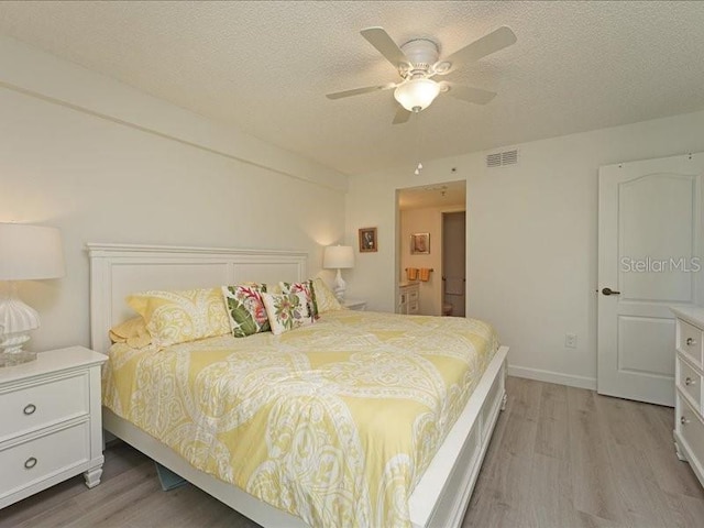 bedroom featuring light wood-style floors, visible vents, and a textured ceiling