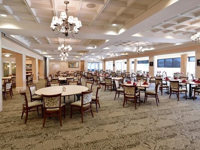 carpeted dining room with a healthy amount of sunlight, an inviting chandelier, coffered ceiling, and beamed ceiling