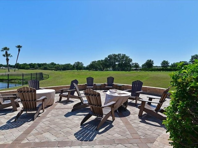 view of patio / terrace featuring a water view, an outdoor fire pit, fence, and a rural view