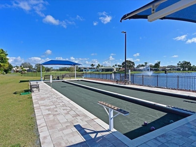 dock area with a water view, fence, and a lawn