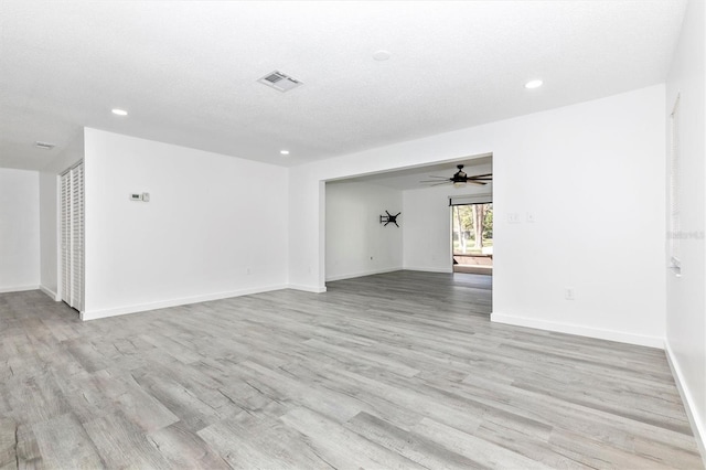 unfurnished room featuring visible vents, light wood-style flooring, a textured ceiling, recessed lighting, and baseboards