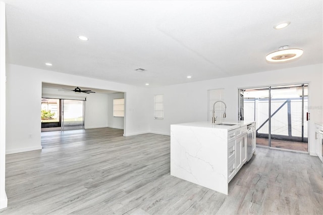 kitchen featuring a wealth of natural light, light wood finished floors, open floor plan, and a sink