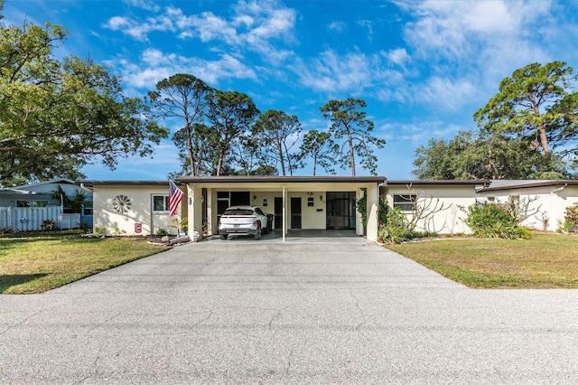 ranch-style home featuring stucco siding, aphalt driveway, fence, a front yard, and a carport