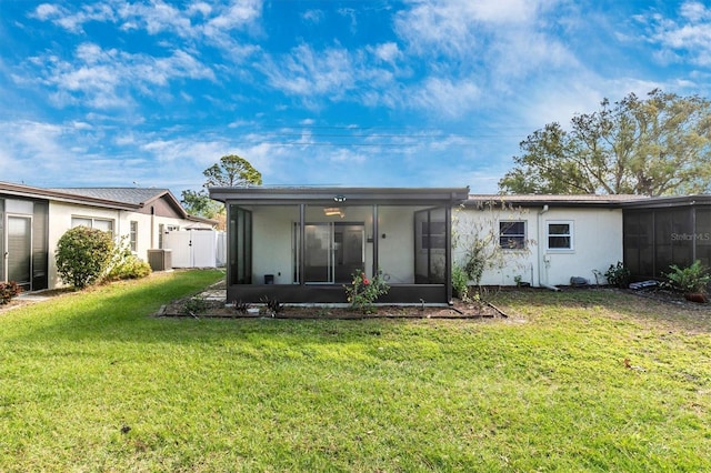 back of property with fence, a yard, and a sunroom