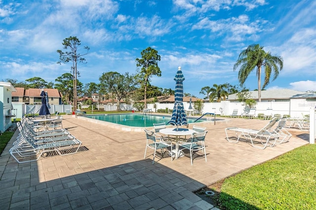 community pool with a patio area and fence