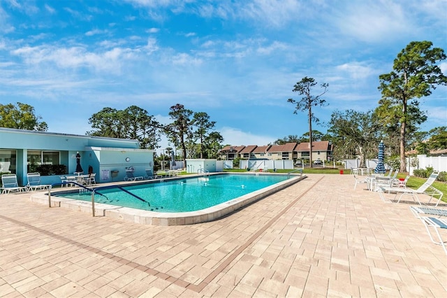 community pool with a patio area and fence