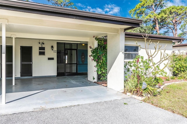 view of exterior entry featuring an attached carport and stucco siding