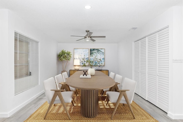 dining area with light wood finished floors, visible vents, a ceiling fan, and baseboards