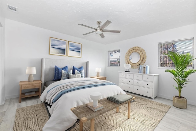 bedroom with light wood finished floors, visible vents, and baseboards