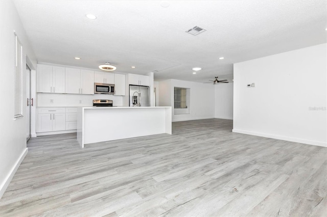 kitchen featuring white cabinetry, visible vents, open floor plan, and stainless steel appliances