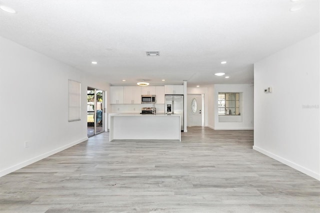 unfurnished living room with baseboards, visible vents, light wood-style flooring, recessed lighting, and a textured ceiling