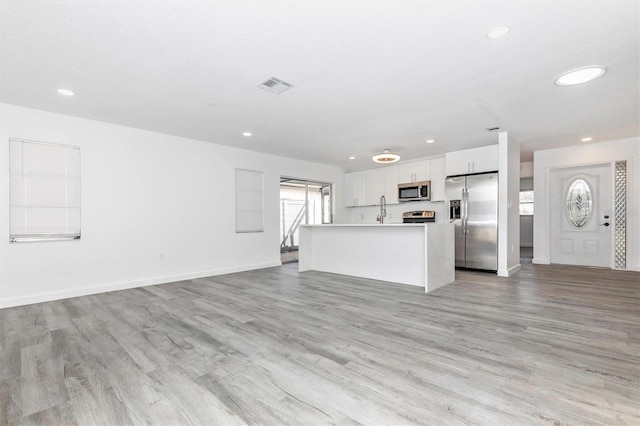 unfurnished living room with light wood-style flooring, recessed lighting, visible vents, and a sink