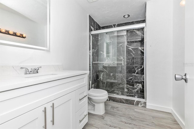 full bath featuring vanity, wood finished floors, a marble finish shower, a textured ceiling, and toilet