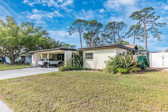 view of front of home with an attached carport, driveway, a front yard, and stucco siding