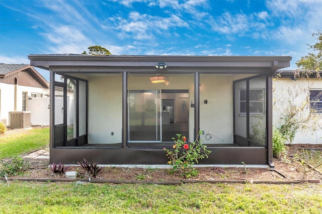 rear view of property with stucco siding, cooling unit, and a sunroom