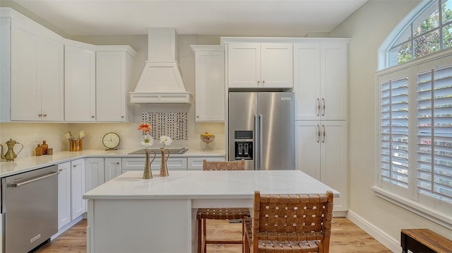 4060 Penshurst Park, Sarasota, FL 34235 - kitchen with light wood-type flooring, stainless steel appliances, custom exhaust hood, and white cabinets