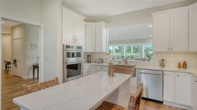 4060 Penshurst Park, Sarasota, FL 34235 - kitchen with white cabinets, light wood-style floors, tasteful backsplash, and stainless steel appliances