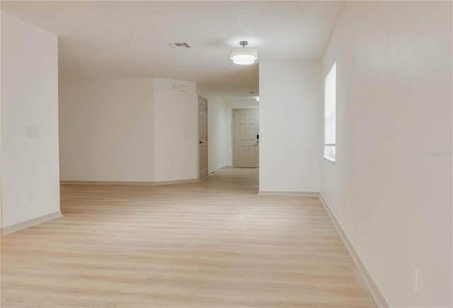 empty room featuring baseboards, visible vents, and light wood finished floors