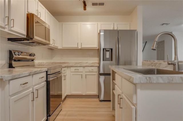 kitchen featuring a sink, visible vents, light wood-style floors, white cabinets, and appliances with stainless steel finishes