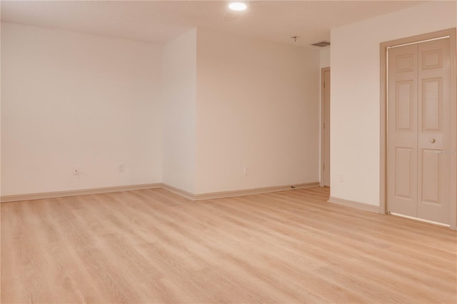 spare room featuring light wood-style flooring, visible vents, and baseboards