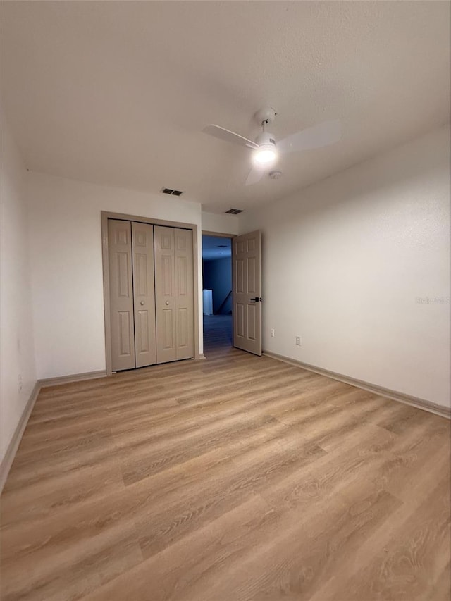 unfurnished bedroom featuring a closet, visible vents, baseboards, and light wood finished floors