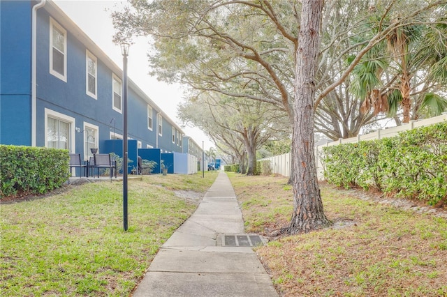 view of property's community with a lawn and fence