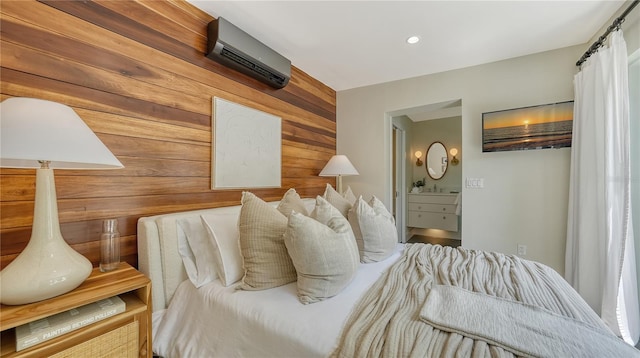 bedroom with connected bathroom, a wall unit AC, and wood walls