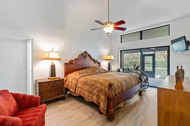 bedroom featuring a towering ceiling, access to outside, ceiling fan, and light wood-type flooring