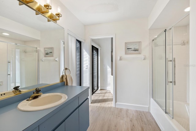 bathroom featuring vanity, hardwood / wood-style flooring, and shower / bath combination with glass door