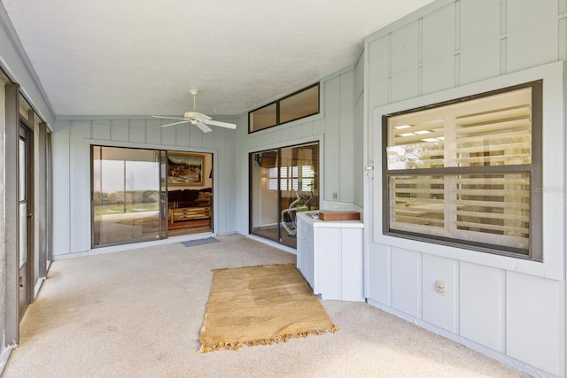 unfurnished sunroom featuring ceiling fan