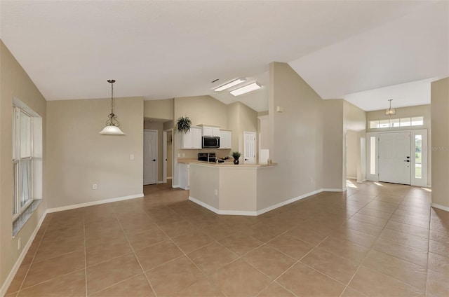 kitchen with pendant lighting, light tile patterned floors, lofted ceiling, white cabinetry, and stove