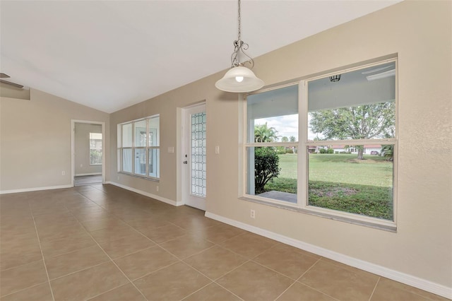 empty room with lofted ceiling, tile patterned flooring, and plenty of natural light