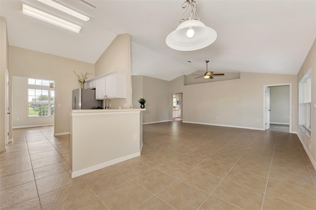 kitchen featuring vaulted ceiling, light tile patterned floors, stainless steel fridge, ceiling fan, and white cabinets