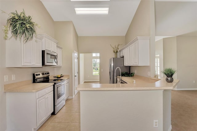 kitchen with light tile patterned flooring, kitchen peninsula, white cabinets, and appliances with stainless steel finishes