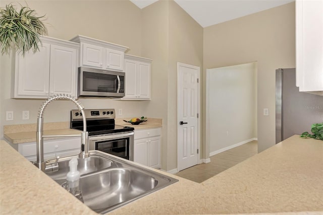 kitchen featuring stainless steel appliances, sink, and white cabinets