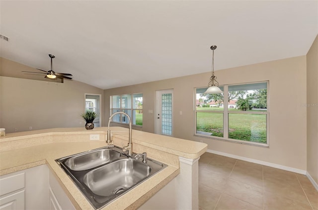 kitchen featuring lofted ceiling, sink, white cabinetry, light tile patterned floors, and pendant lighting