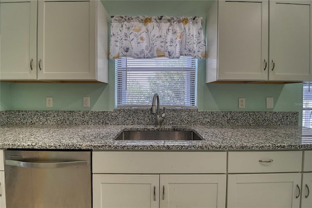 kitchen with light stone countertops, sink, stainless steel dishwasher, and white cabinets