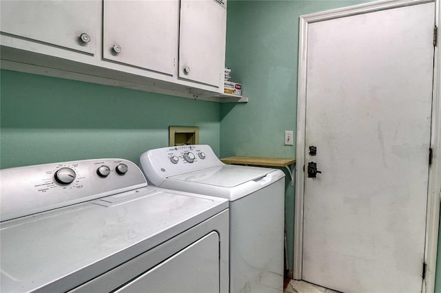 washroom featuring cabinets and washer and clothes dryer