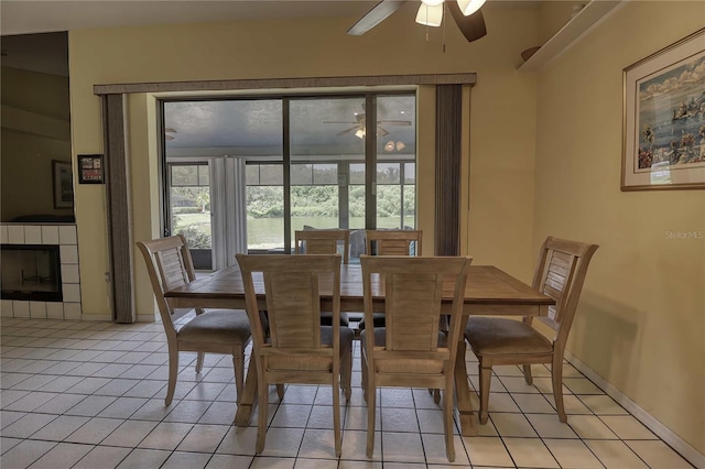 dining area with light tile patterned flooring, ceiling fan, and a fireplace