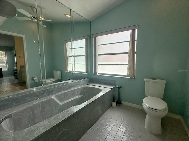 bathroom with lofted ceiling, a wealth of natural light, a washtub, and toilet