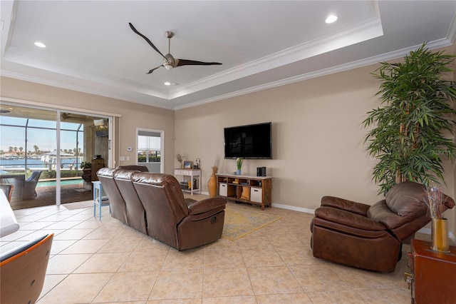 living room with crown molding, a raised ceiling, ceiling fan, and light tile patterned floors